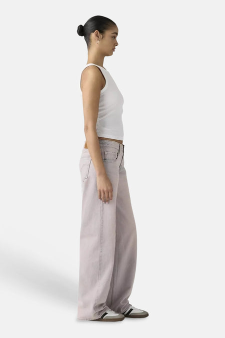 Pantalon rose de Levi's®, coupe ample, montré de profil avec un haut blanc côtelé et des baskets.