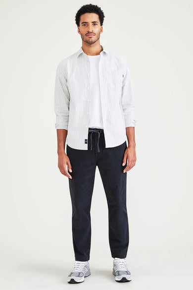 Pantalon bleu de DOCKERS, vu d'arrière, avec un t-shirt blanc et des chaussures de sport grises.