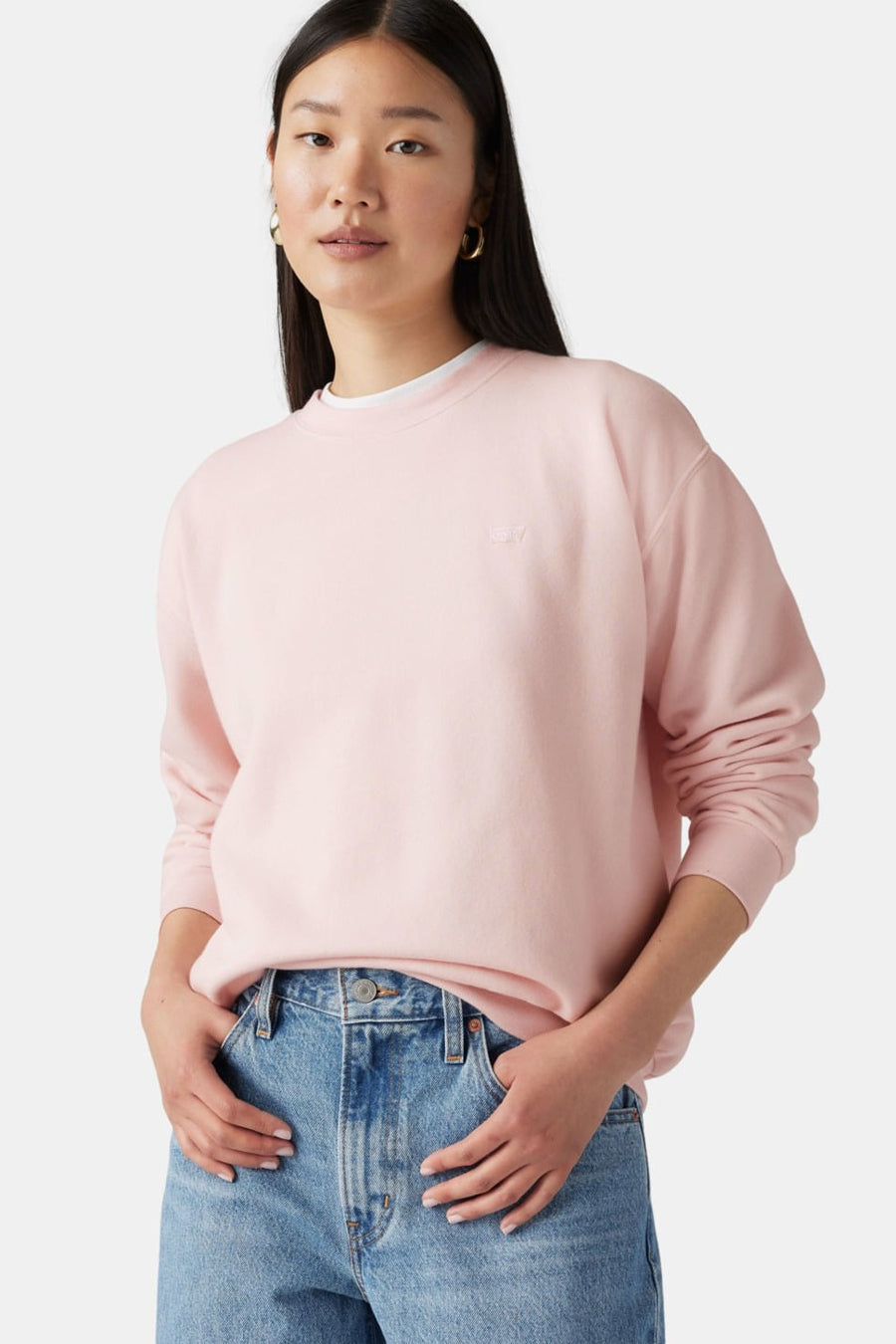 Vrouw met roze sweatshirt en blauwe jeans.
