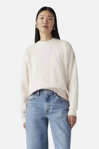 Witte ronde hals sweater van Levi's® met comfortabele pasvorm, gedragen met blauwe jeans en gouden oorbellen, front view.
