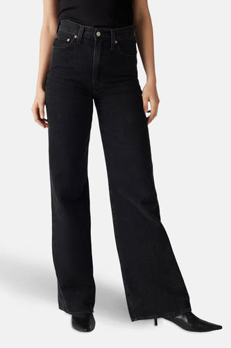 Jean délavé noir de Levi's, porté avec un haut noir et des chaussures noires, en vue latérale.