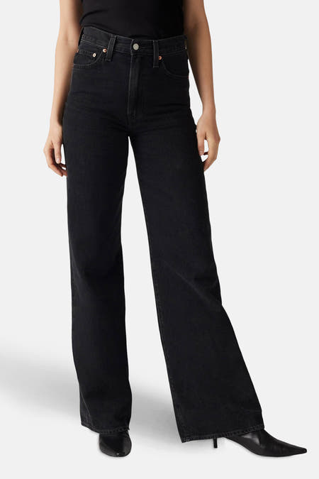 Jean délavé noir de Levi's, porté avec un haut noir et des chaussures noires, en vue latérale.