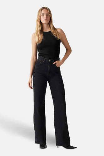 Jean noir délavé de Levi's, associé à une chemise en coton rayé noir et des baskets noires.