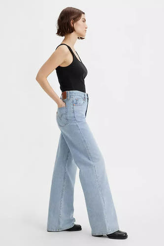 Jean en denim bleu clair à larges jambes de Levi's, avec un tank-top noir et des chaussures noires.