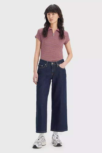 Jeans larges en denim bleu foncé de Levi's®, avec des coutures subtiles et portées avec un polo rayé.