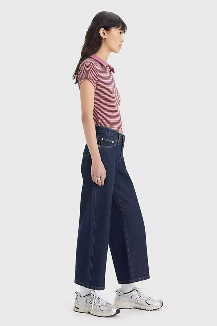 Jean ample bleu foncé de Levi's, avec un délavage foncé, combiné avec un haut rayé et des baskets blanches.