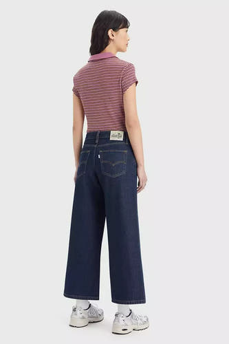 Wijde jeans van donkerblauw denim van Levi's®, met een subtiele stiksels en gedragen met een gestreepte polo.