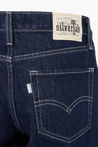 Jean large bleu foncé de Levi's, avec des surpiqûres claires sur la poche arrière et un patch en cuir.