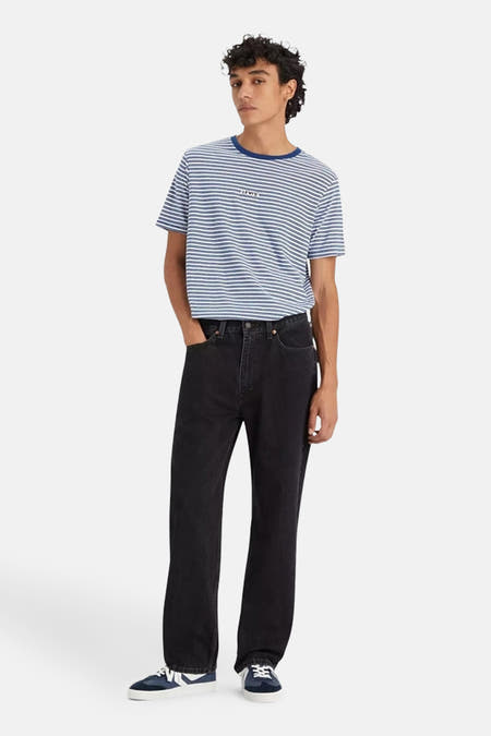 Jean droit en denim noir de Levi's, associé à un t-shirt rayé et des baskets bleues.