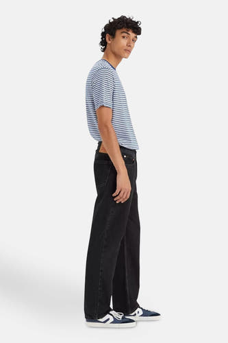 Jean droit en denim noir de Levi's®, associé à un t-shirt rayé et des baskets bleu et blanc, vue latérale.