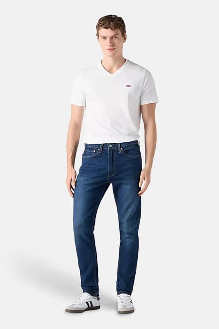 Jeans straight mid blue denim van Levi's®, gedragen met een wit V-hals T-shirt en witte sneakers.