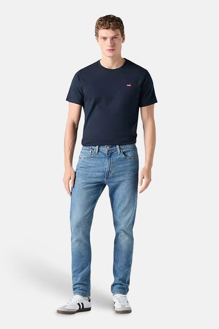 Rechte jeans in lichtblauw denim van Levi's, gedragen met een donkerblauw T-shirt en witte sneakers.