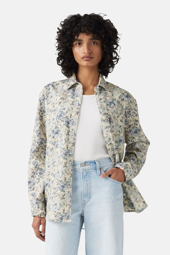 Blauw jeanshemd van Levi's, met bloemenprint, gedragen over een wit shirt en een lichtblauwe jeans.
