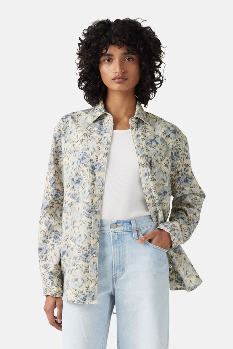 Blauw jeanshemd van Levi's, met bloemenprint, gedragen over een wit shirt en een lichtblauwe jeans.
