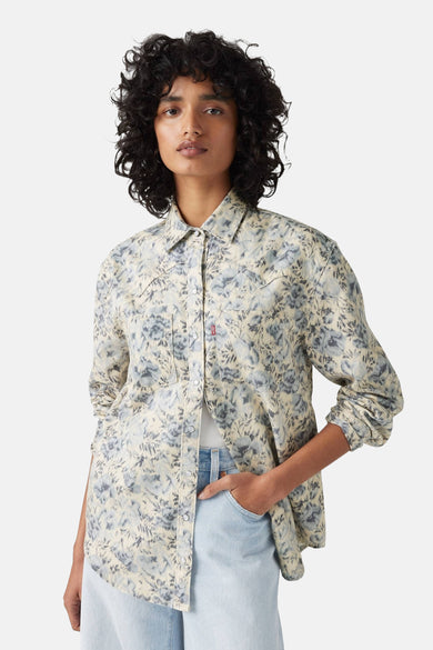 Vrouw met bloemenblouse en jeans.