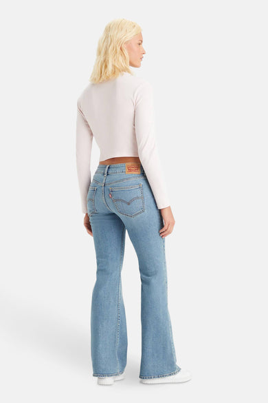 Jean flare en denim bleu clair de Levi's, vu de depuis l'arrière, avec un t-shirt rose à manches longues.