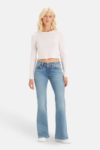 Jean flare en denim bleu clair de Levi's, associé à un haut rose pâle et des baskets blanches.