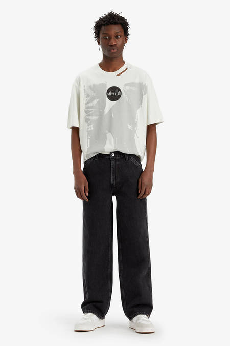 Jean droit noir de Levi's®, avec des baskets blanches et un T-shirt blanc imprimé.
