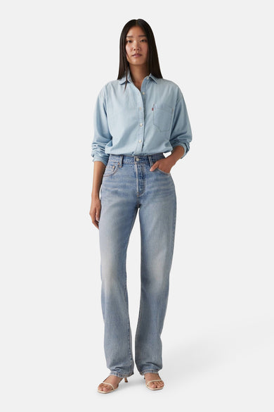 Jean droit en denim bleu clair de Levi's, avec une taille haute tailleurée et stylé avec un chemisier bleu clair.