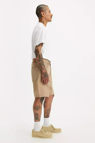 Short beige de Levi's, porté avec un t-shirt blanc, des chaussettes blanches et des chaussures beige, en vue latérale.