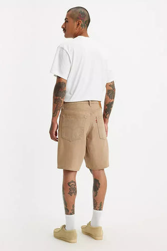 Short beige de Levi's, avec des poches arrière et porté avec un T-shirt blanc et des chaussures beige.
