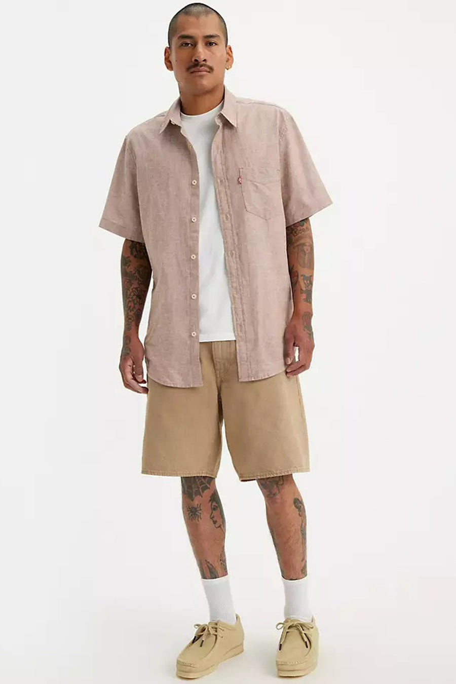 Short beige de Levi's®, porté avec un T-shirt blanc, une chemise claire et des chaussures crème.