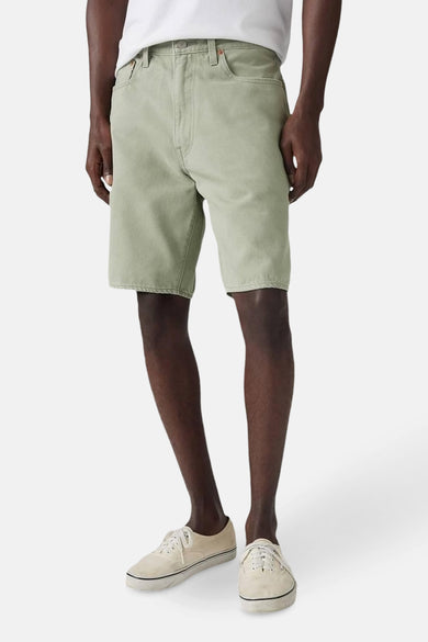 Persoon draagt kaki shorts en crèmekleurige schoenen.