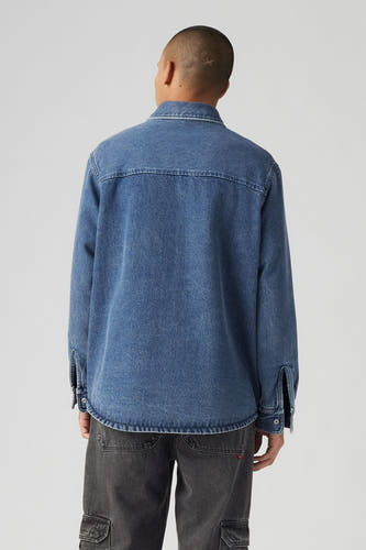 T-shirt en jeans en denim bleu moyen de Levi's, vu de derrière, avec un pantalon gris foncé.