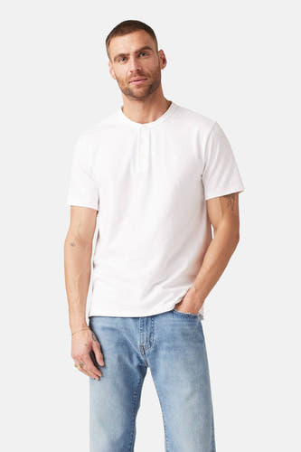 T-shirt blanc à manches courtes de Levi's, porté avec un jeans bleu et des bijoux en or.