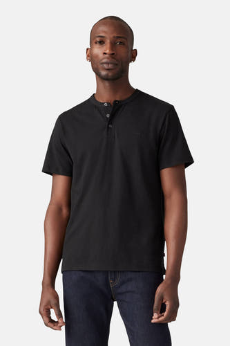 T-shirt noir à manches courtes de Levi's, avec des boutons et porté avec un jeans bleu foncé.