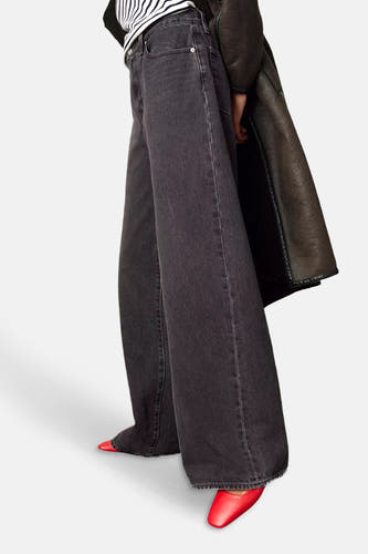 Jean droit noir de Levi's®, avec des jambes larges et des chaussures rouges.