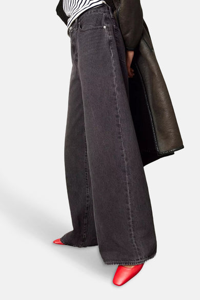 Jean droit noir de Levi's®, avec des jambes larges et des chaussures rouges.