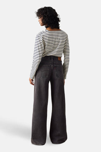 Jean droit noir de Levi's, avec des jambes larges et un chemisier rayé.