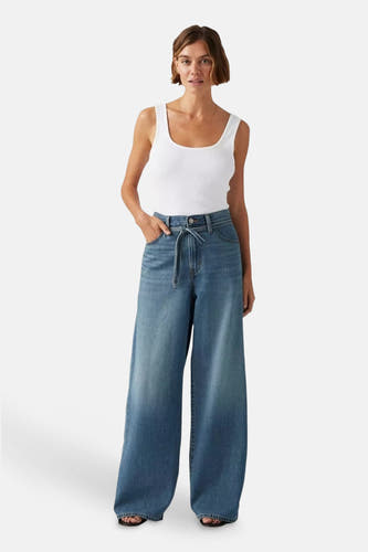 Jean droit en denim bleu moyen de Levi's, avec une ceinture élastique et un t-shirt blanc.