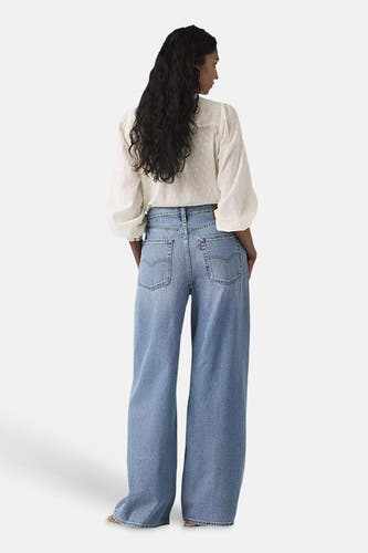 Jean droit bleu de Levi's, vu de dos, avec poches italiennes et une blouse blanche.