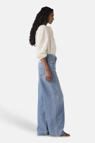 Jean droit bleu de Levi's, avec une coupe décontractée et porté avec une blouse blanche.