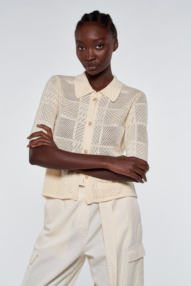 Gilet tricoté écru avec motif ajouré et fermeture à boutons d'Astrid Black Label, porté avec un pantalon assorti, vue de face
