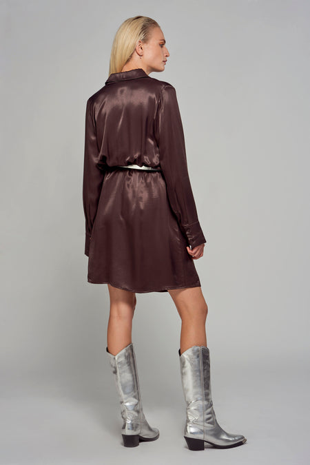 Manteau brun à longues manches d'Astrid Black Label, avec une ceinture et des chaussures en argent.