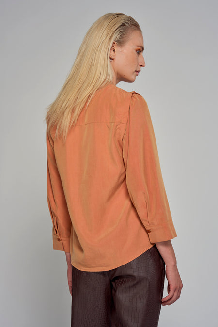 Blouse orange à manches trois-quarts d'Astrid Black Label, vue de derrière, portée avec un pantalon marron imprimé crocodile.
