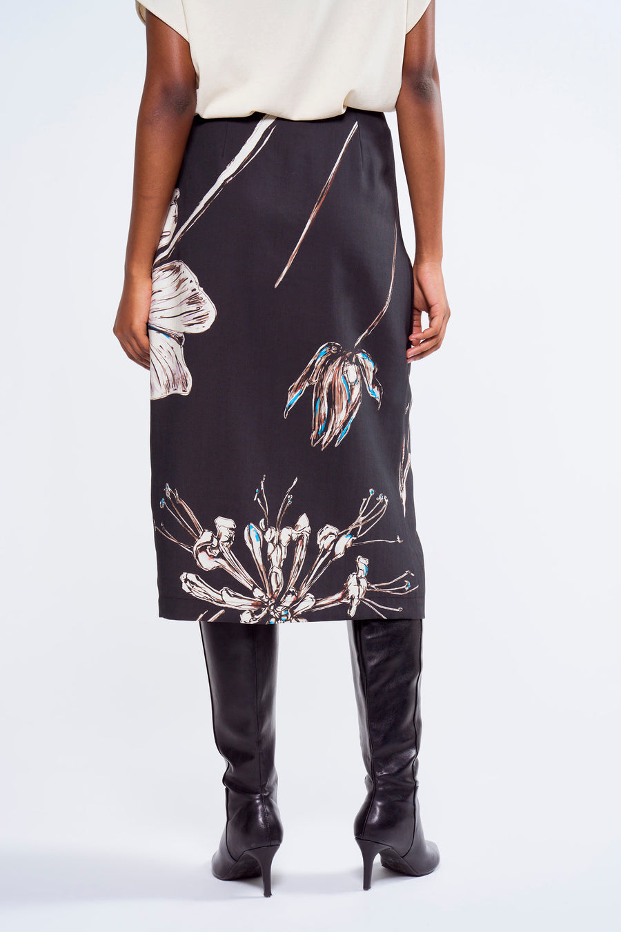 Robe multicolore d'Astrid Black Label avec un imprimé de fleurs, portée avec des bottes en cuir noires.