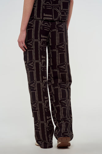 Een persoon die een donkere set bedrukte kleding en schoenen draagt.