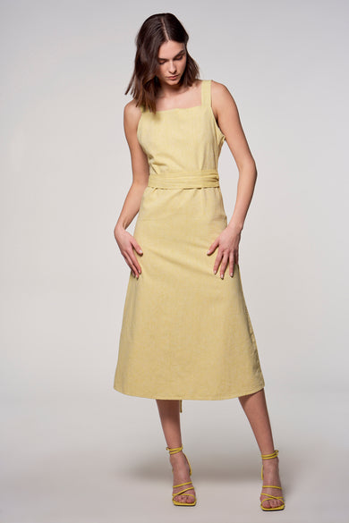Jupe sans manches de Astrid Black Label, avec une ceinture de la même couleur et des talons jaunes.