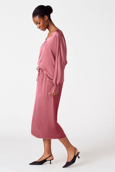 Robe rose d'Astrid Black Label, portée avec des sandales à brides noires, en vue latérale.