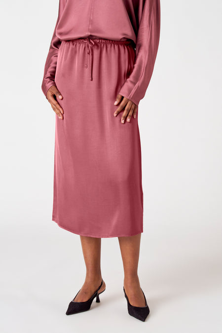Robe rose d'Astrid Black Label, avec une ceinture élastique et des talons assortis.