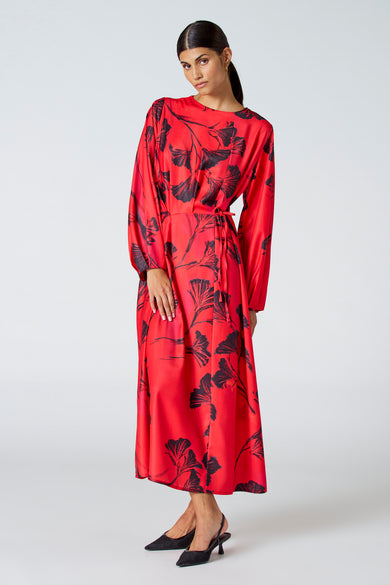 Robe rouge à longues manches d'Astrid Black Label, avec un motif de feuille foncé et une ceinture élastique.
