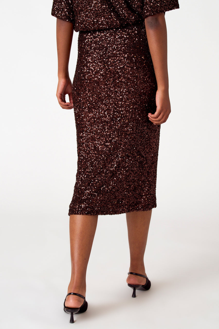 Vrouw, jurk met bruine pailletten, hoge hakken.