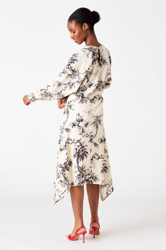 Vrouw in jurk met print, rode hakken, staand op witte achtergrond.