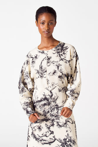 Model in een crèmekleurige jurk met zwart patroon.