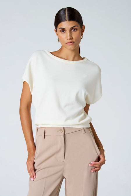 Tunique écru d'Astrid Black Label, associée à un pantalon et des bijoux en or.