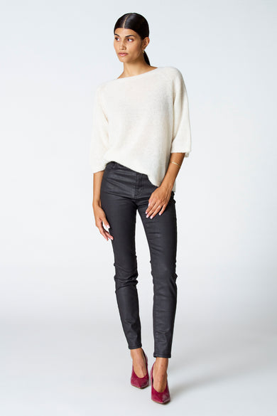 T-shirt écru avec col rond d'Astrid Black Label, porté avec un pantalon noir brillant et des baskets roses.